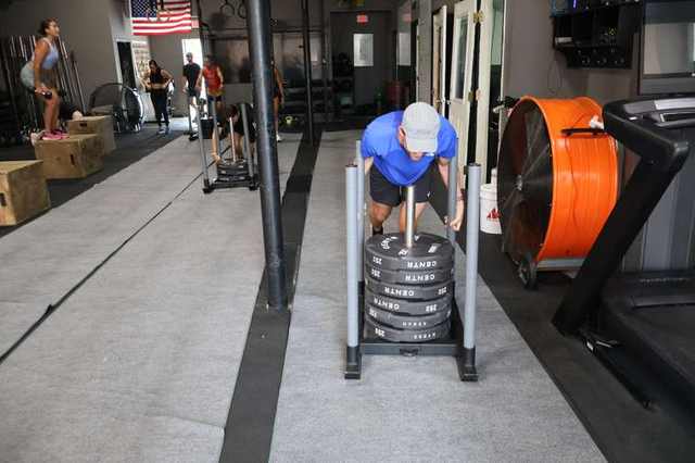 Athlete driving a HYROX-plate sled during class at FTX Fort Worth