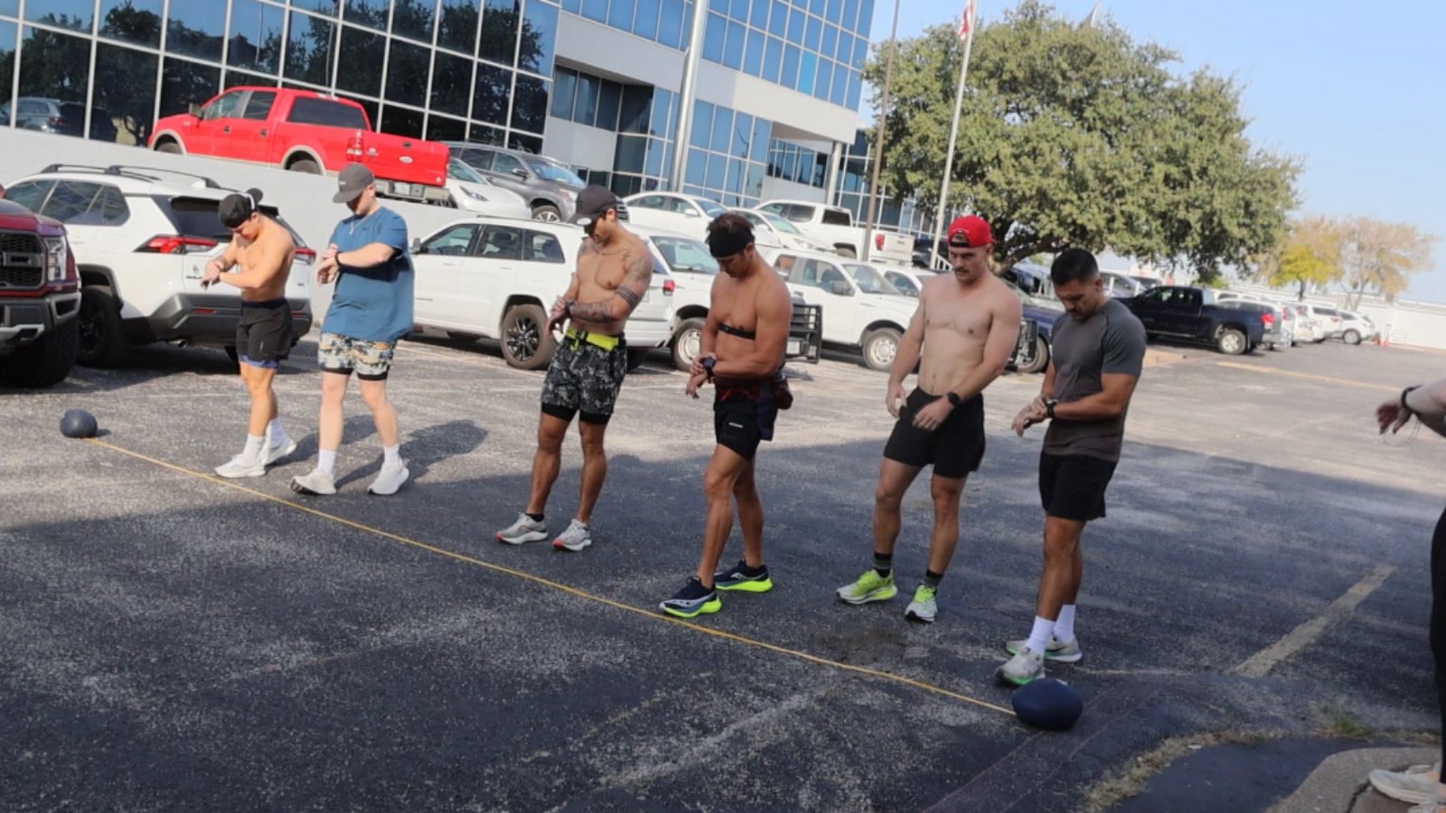 FTX athletes checking watches before a run interval outside the gym